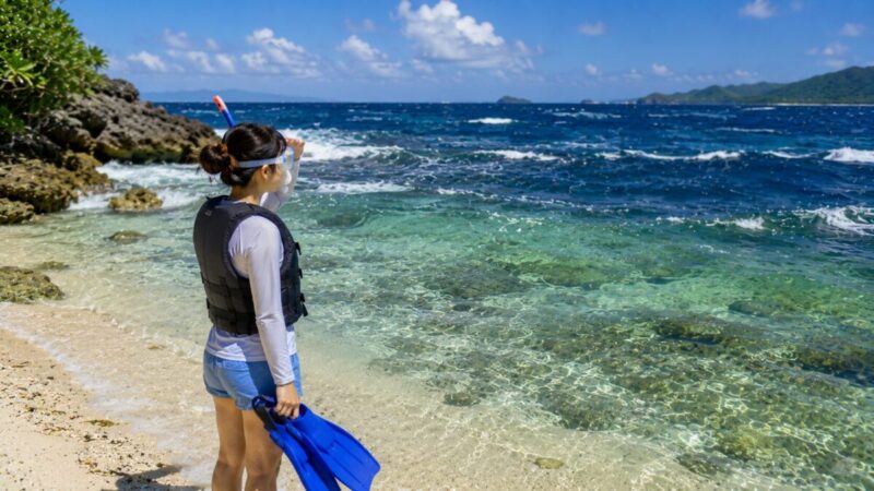 沖の波や風を岸から確認し、フィンを持って入水を見合わせるシュノーケラー。