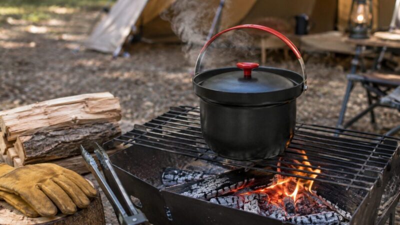 焚き火台の焼き網にライスクッカーを置き、薪の炎と熾火で火加減を調整している様子