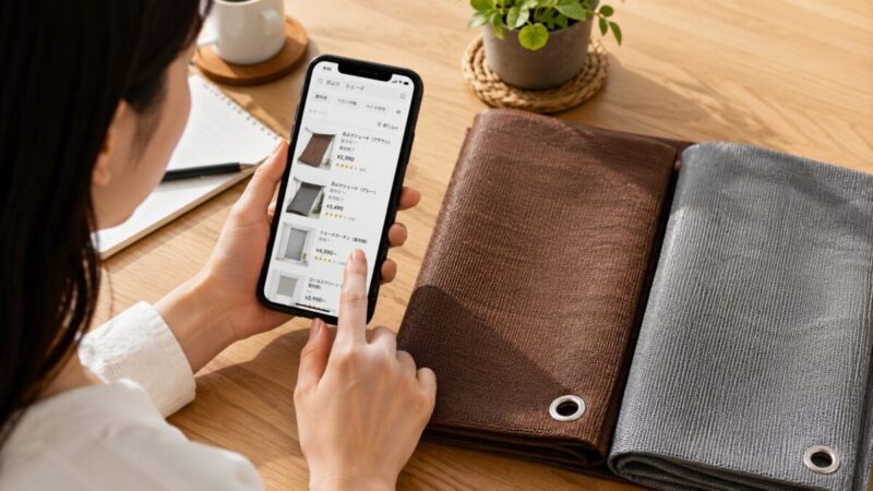 スマートフォンで屋外用日よけシェードの販売状況を確認しながらブラウンとグレーの生地を比較する様子