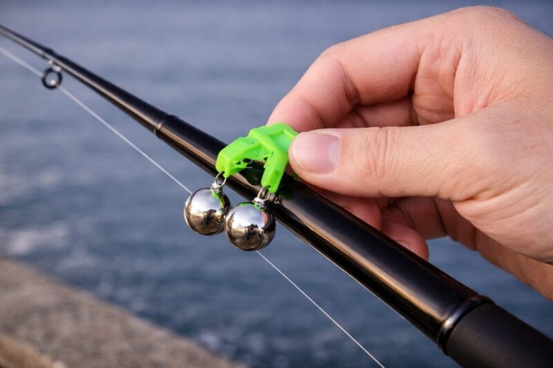 クリップ式の釣り鈴を竿にまっすぐ固定している手元イメージ