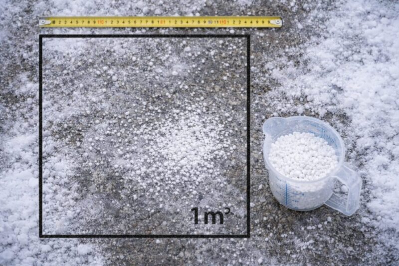 散布範囲と量の目安を測りながら、融雪剤を少量だけ撒いている様子