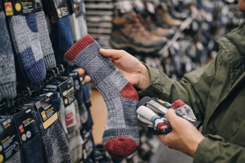 売り場で登山用の靴下を手に取り、厚みを確かめている様子