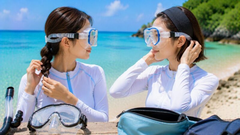 低い三つ編みとヘアバンドで髪を整え、マスクの装着位置を確認する女性二人