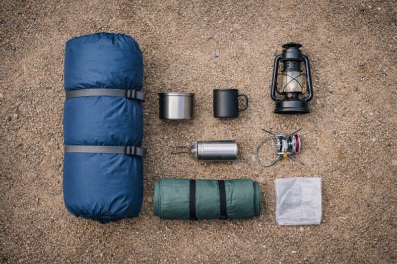寝袋やマット、ランタン、調理道具など最低限の装備を地面に並べた様子