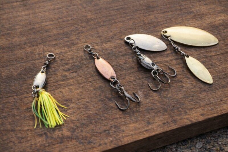 木のテーブルに並べた複数のスピナー系ルアーを上から見た比較イメージ