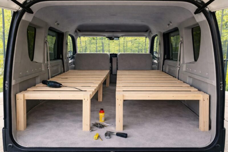 軽バンの車内で幅広の木製ベッドを組み立てている途中のイメージ