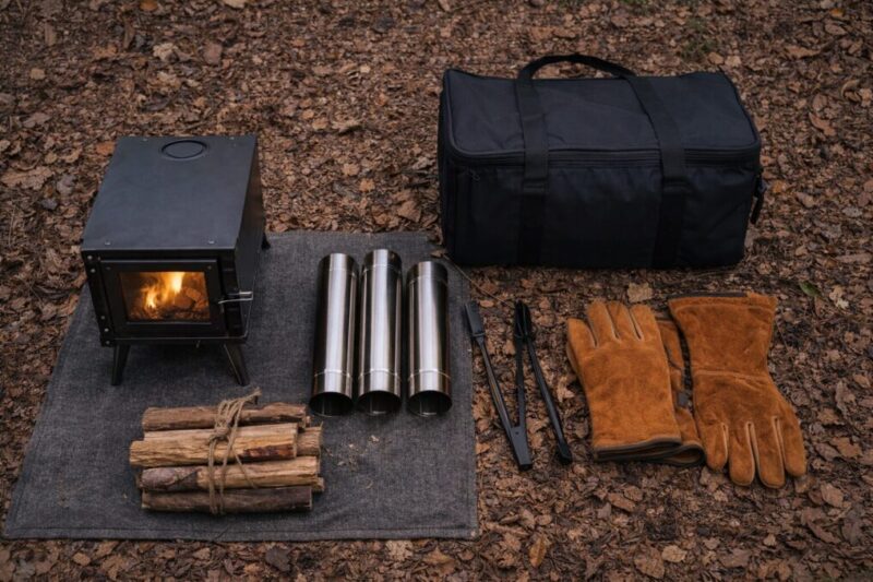 薪ストーブ本体と煙突パイプ、手袋などを並べ、徒歩キャンプ向けに装備をコンパクトにまとめた様子