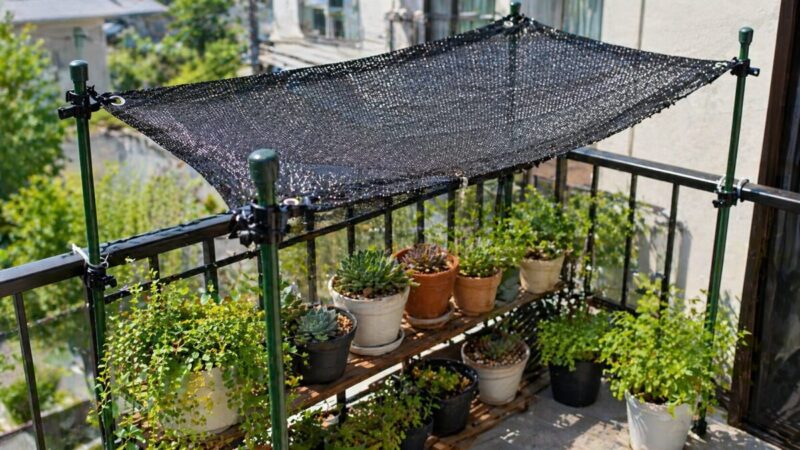ベランダの植物棚に遮光ネットを張り、鉢植えや多肉植物の日差しをやわらげている様子