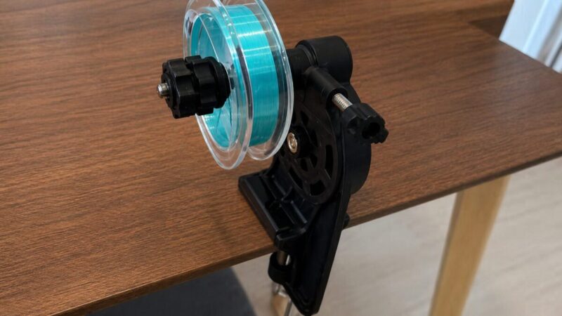 自宅の作業テーブルでライン巻き替え器具にターコイズブルーの釣り糸をセットしている様子。