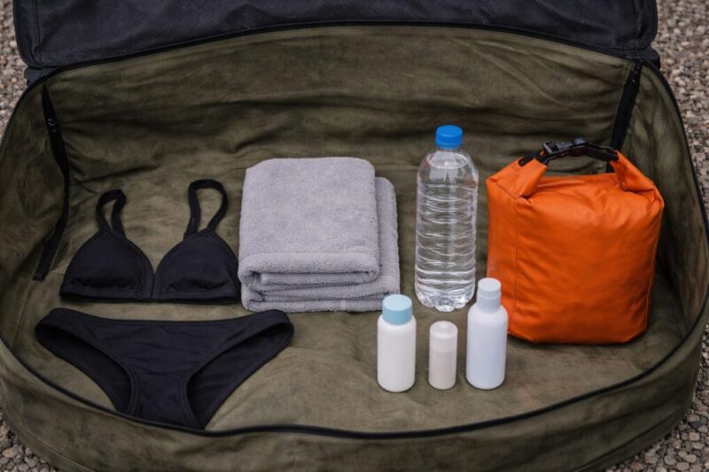 グランピングサウナに持っていく水着やタオル、防水バッグ、飲み物、スキンケア用品をまとめたイメージ