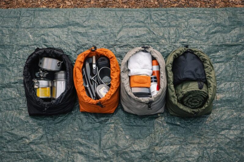 グランドシート上にスタッフサックを並べ、道具をカテゴリ別に整理したUL装備の置き場づくり