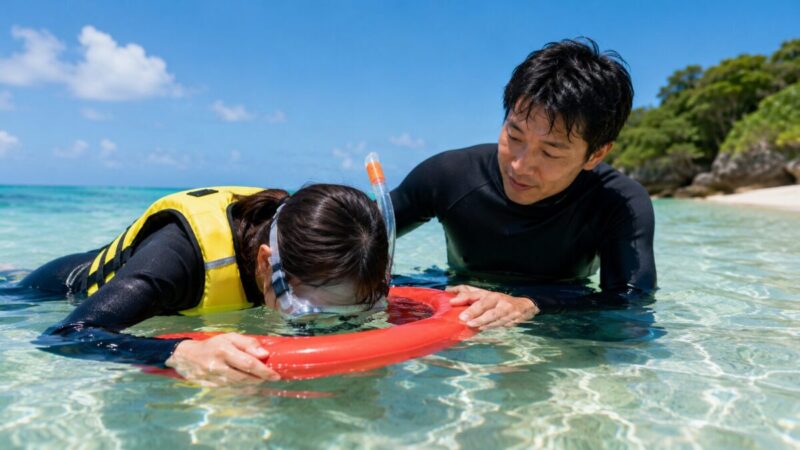 水が怖い初心者がフロートにつかまり、インストラクターに見守られながら浅瀬でスノーケル呼吸を練習する様子