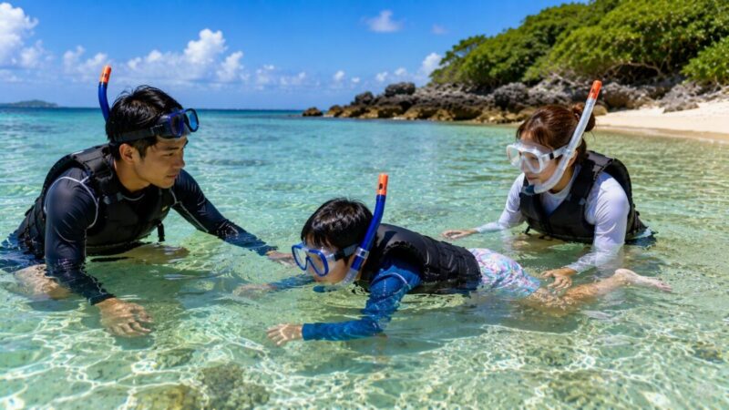 ライフジャケットを着用し、ガイドと保護者に見守られながら浅瀬で練習する子ども。