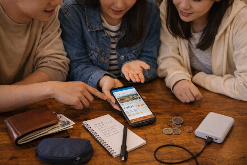 学割や早割を比較してグランピングの予算を考える学生のイメージ