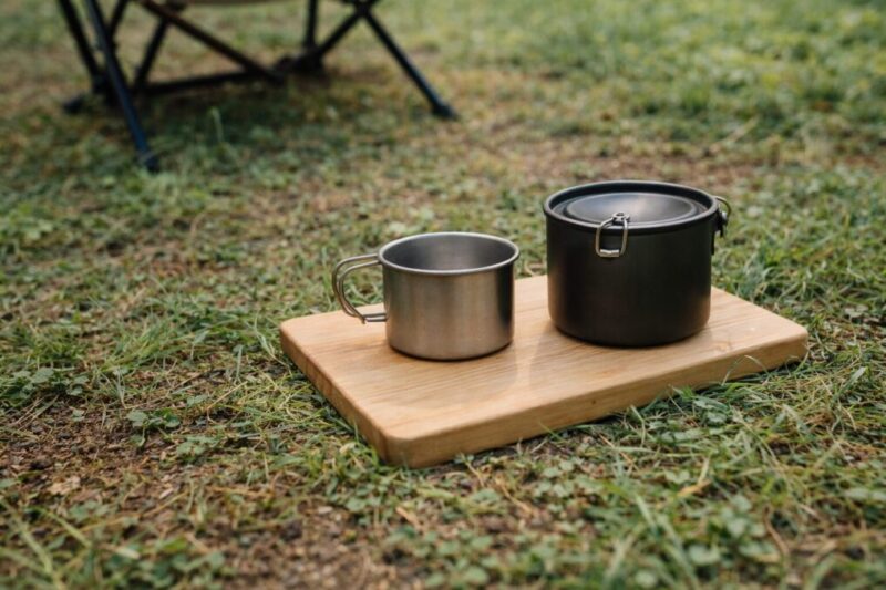まな板を簡易テーブルとして使い、カップやクッカーを置いているソロキャンプの様子