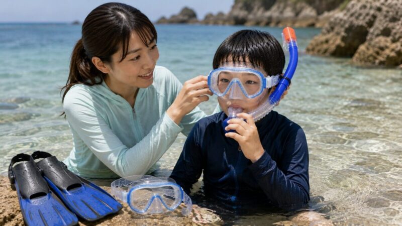 浅瀬でシュノーケルの装着と呼吸を確認する親子