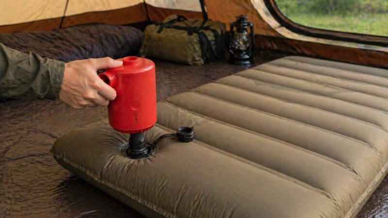 インフレーターマットのバルブに小型ポンプを接続して空気を入れている手元