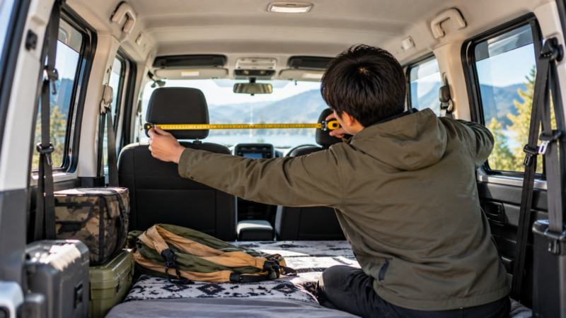 車中泊用ハンモックを取り付ける前に車内寸法をメジャーで測る様子