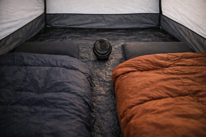 テント内で寝袋とマットを壁から離して配置し、小型ファンで空気を循環させて結露を減らす工夫のイメージ