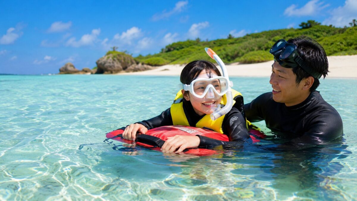 泳げない初心者がライフジャケットとフロートを使い、浅瀬でガイドの支援を受けながらシュノーケリングを練習する様子