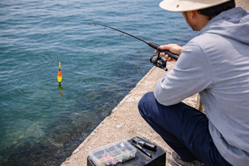 堤防で海面に浮かぶウキを見ながら釣りを楽しむ実釣イメージ