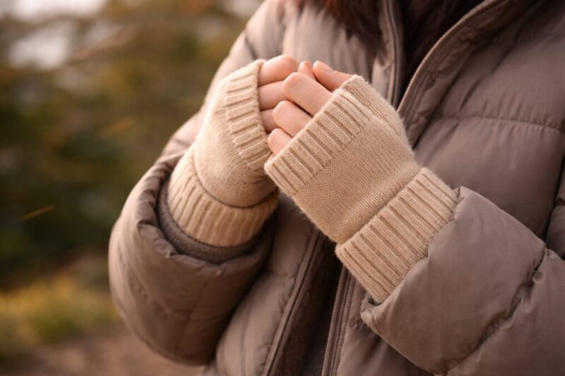 風のある屋外で袖口のすき間を減らして保温する手元のイメージ
