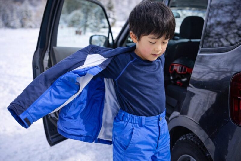 車のそばで子どもが上着を脱いで体温調整している様子