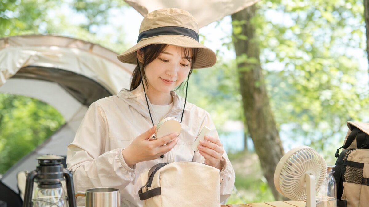 外遊び中に顔の日焼け止めを塗り直すためのUVパウダーとスティックを準備している様子