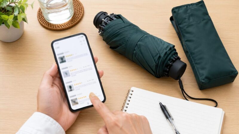 折りたたみ日傘と収納袋を並べてスマホで口コミを確認している様子
