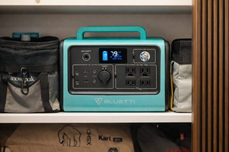 収納棚にポータブル電源をしまい、ケーブル類の準備や置き場所を確認しているイメージ