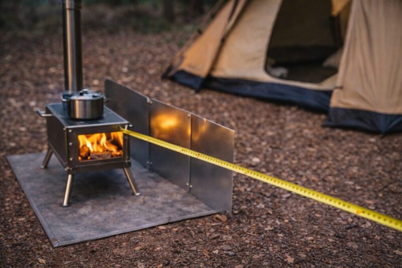 薪ストーブとテントの距離を測り、遮熱板で熱対策をしているイメージ。