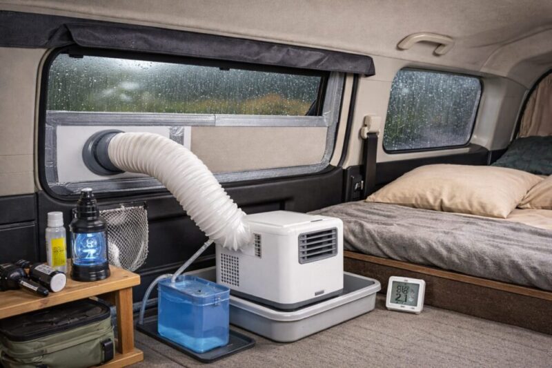 車中泊用の小型冷房機のまわりに排水容器、湿度計、虫対策用品を並べ、結露や虫の侵入に備えた使い方を示したイメージ