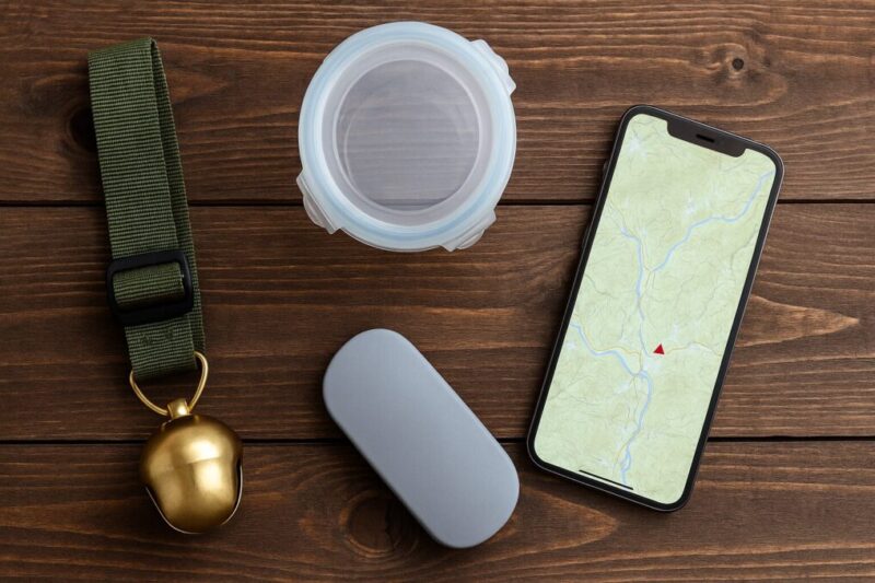 遭遇回避の準備品（熊鈴・密閉容器・小物ケース・地図アプリ表示のスマホ）を木の面に並べた俯瞰ショット