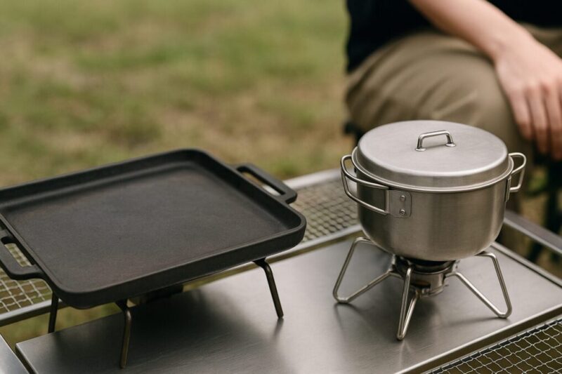 長く使える無地の鉄板ギアとステンレス鍋のディテールを屋外で切り取ったイメージ。