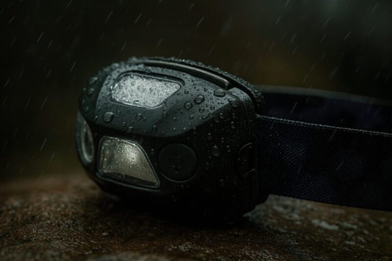 雨に濡れたヘッドランプの接写。USBポートカバーを閉めた防水イメージと注意点を示す写真。